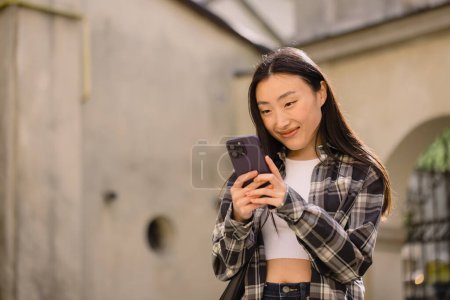 Foto de Retrato de una hermosa mujer coreana en la calle del casco antiguo. Mujer asiática en ropa casual hablando por teléfono, tecnología moderna y estilo de vida. - Imagen libre de derechos