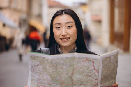Foto de Retrato de una hermosa mujer coreana sosteniendo un mapa en las calles de una antigua ciudad europea. Mujer asiática turista o dama de negocios viajando en Europa. - Imagen libre de derechos