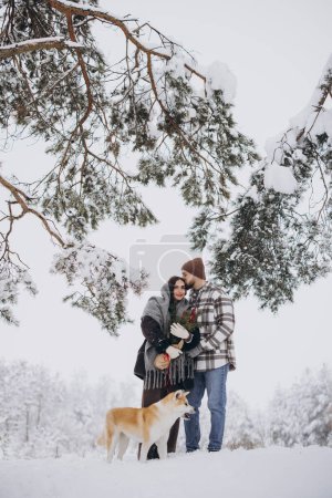 Photo for Happy young couple with akita dog in forest on winter day - Royalty Free Image