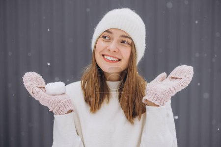 Photo for Happy young woman in knitted mittens catches snowflakes in winter - Royalty Free Image