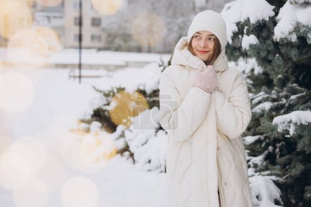Photo for Portrait of a happy beautiful girl in white knitted clothes posing in a winter coat on a snowy day - Royalty Free Image
