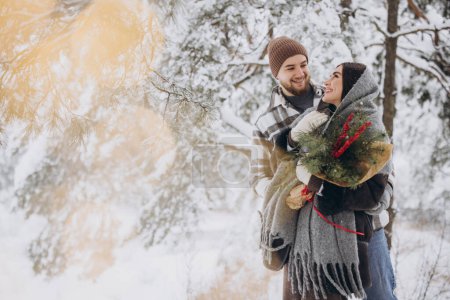Foto de Linda pareja joven enamorada de ramo de pino pasar tiempo en el día de San Valentín en el bosque de invierno nevado en las montañas - Imagen libre de derechos