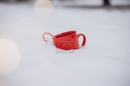 Photo for Red cup of coffee with candy cane on snow in winter - Royalty Free Image