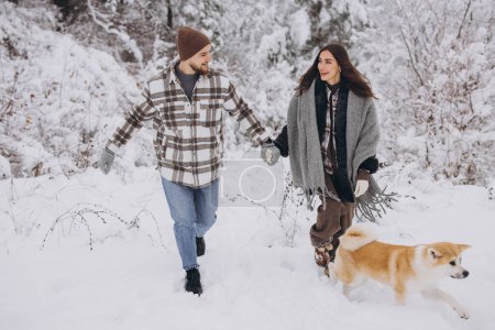 Photo for Happy young couple with akita dog in forest on winter and snowly day - Royalty Free Image
