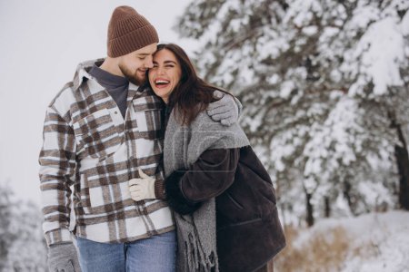 Foto de Una joven pareja feliz y cariñosa caminando en un bosque nevado de invierno en las montañas - Imagen libre de derechos