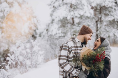 Foto de Linda pareja joven enamorada de ramo de pino pasar tiempo en el día de San Valentín en el bosque de invierno nevado en las montañas - Imagen libre de derechos