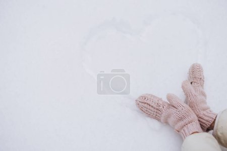 Foto de Las manos femeninas cerca del corazón dibujado sobre la nieve en invierno - Imagen libre de derechos