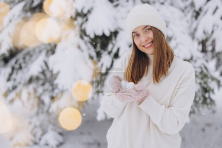Téléchargez les photos : Femme heureuse en mitaines tricotées tenant un cœur de neige par une journée enneigée d'hiver - en image libre de droit