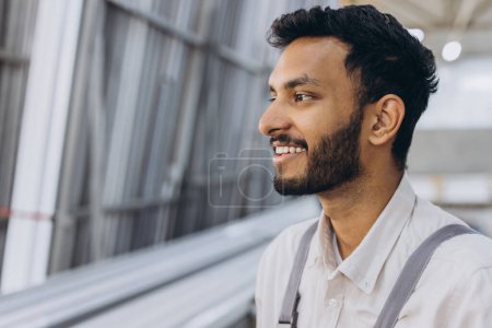 Photo for Portrait of a happy Hindu worker in overalls background of a factory and aluminum frames. - Royalty Free Image