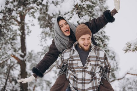 Téléchargez les photos : Un jeune couple heureux et aimant s'amuse dans une forêt enneigée en hiver. - en image libre de droit