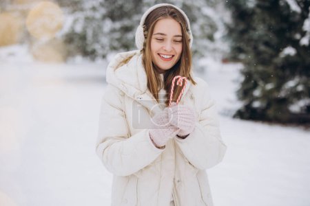 Téléchargez les photos : Une jolie fille en mitaines tricotées tient des cannes de bonbons sous la forme d'un cœur dans le parc d'hiver - en image libre de droit