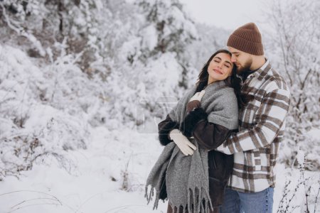 Téléchargez les photos : Portrait d'un jeune couple heureux et aimant s'amusant dans une forêt enneigée - en image libre de droit