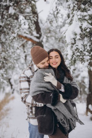 Téléchargez les photos : Portrait d'un jeune couple heureux et aimant s'amusant dans une forêt enneigée - en image libre de droit