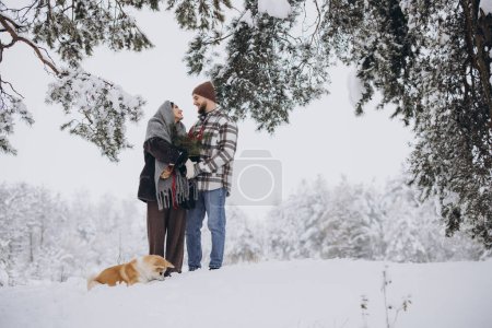 Téléchargez les photos : Joyeux jeune couple avec chien akita en forêt le jour de l'hiver - en image libre de droit