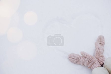 Foto de Las manos femeninas cerca del corazón dibujado sobre la nieve en invierno - Imagen libre de derechos