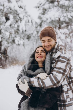 Foto de Una joven pareja feliz y cariñosa se divierte en un bosque nevado en invierno. - Imagen libre de derechos