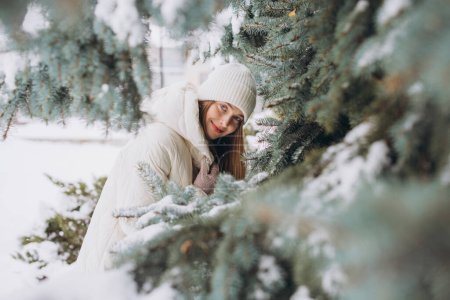 Téléchargez les photos : Portrait d'une belle fille heureuse en tricot blanc posant dans un manteau d'hiver par une journée enneigée - en image libre de droit