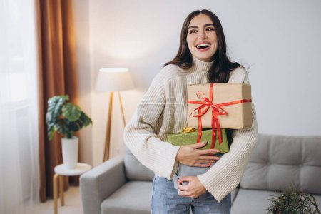 Photo for Beautiful happy woman is wrapping and holding Christmas presents at home - Royalty Free Image
