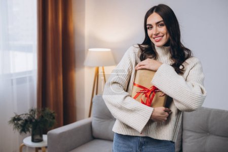Photo for Beautiful happy woman holding or unwrapping New Year or Christmas presents at home - Royalty Free Image