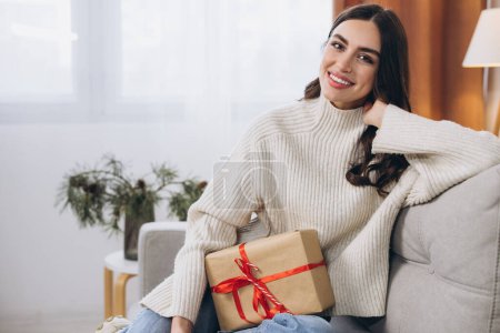 Foto de Hermosa mujer feliz desenvolviendo regalos de Año Nuevo o Navidad en casa en el sofá - Imagen libre de derechos