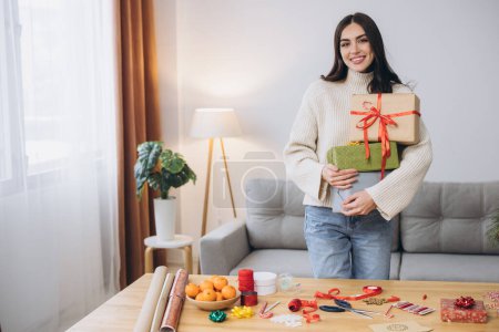 Foto de Hermosa mujer feliz está envolviendo y la celebración de regalos de Navidad en casa - Imagen libre de derechos