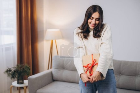 Foto de Hermosa mujer feliz sosteniendo o desenvolviendo regalos de Año Nuevo o Navidad en casa - Imagen libre de derechos