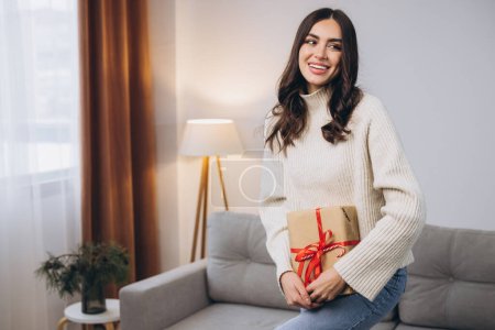 Téléchargez les photos : Belle femme heureuse tenant ou déballer des cadeaux de Nouvel An ou de Noël à la maison - en image libre de droit