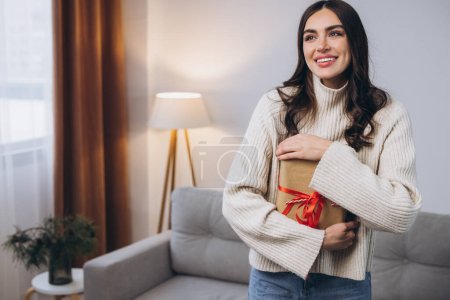 Téléchargez les photos : Belle femme heureuse tenant ou déballer des cadeaux de Nouvel An ou de Noël à la maison - en image libre de droit
