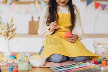 Photo for Happy easter! A beautiful child girl sitting on the table with decoratioons and painting colorful eggs. Cute child girl wearing bunny ears on Easter day. - Royalty Free Image