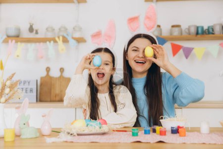 Photo for Mother and her daughter holding colorful eggs. Happy family preparing for Easter. Cute little child girl wearing bunny ears. - Royalty Free Image