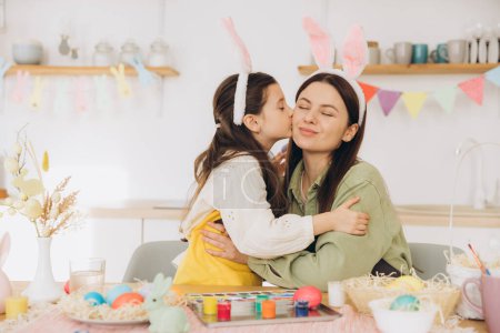 Photo for Mother and her daughter painting eggs. Happy family preparing for Easter. Cute little child girl wearing bunny ears. - Royalty Free Image