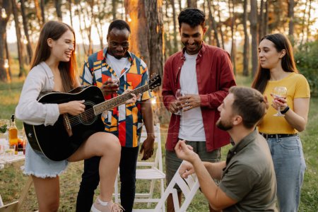 Foto de Atractiva mujer hipster tocando la guitarra ganando a los hombres en la cena con amigos multirraciales - Imagen libre de derechos