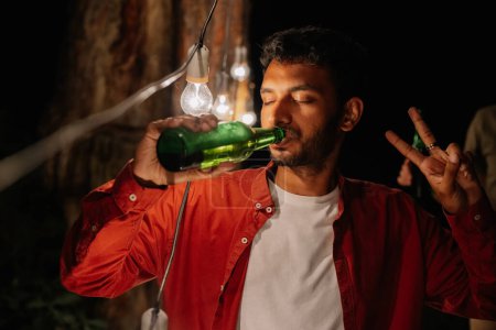 Photo for Indian man drinking beer non-stop, drinking a lot of beer at a party with friends, addicted to alcohol - Royalty Free Image