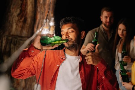 Photo for Indian man drinking beer non-stop, drinking a lot of beer at a party with friends, addicted to alcohol - Royalty Free Image