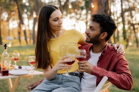 Téléchargez les photos : Heureux couple multiracial boire du vin ensemble lors d'une fête avec des amis - en image libre de droit