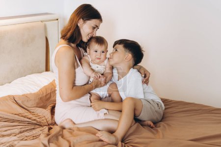 Photo for Happy young mother spending time with her children in the bedroom - Royalty Free Image