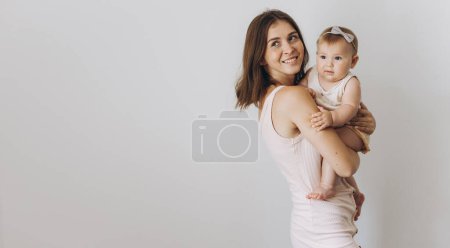 Téléchargez les photos : Joyeux jeune mère avec son adorable bébé fille sur fond blanc - en image libre de droit