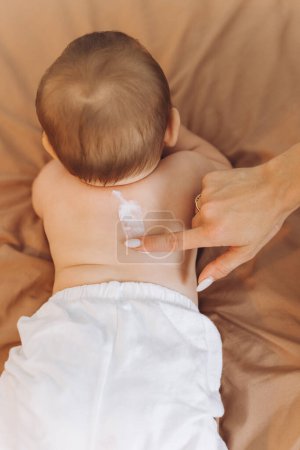 Photo for Happy mother applying cream on her baby girl's body - Royalty Free Image