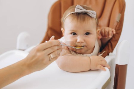 Photo for Mother feeding healthy food to her adorable little daughter sitting in high chair - Royalty Free Image