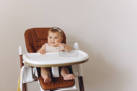 Photo for Happy little baby girl sitting in high chair in kitchen at home - Royalty Free Image