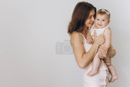 Téléchargez les photos : Joyeux jeune mère avec son adorable bébé fille sur fond blanc - en image libre de droit