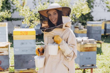 Photo for Happy smiling female beekeeper holding ready organic honey made in bee farm - Royalty Free Image