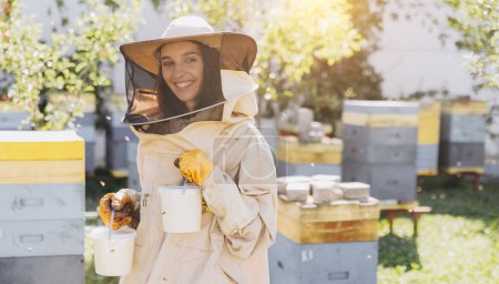 Foto de Feliz hembra apicultora sonriente sosteniendo miel orgánica preparada hecha en la granja de abejas - Imagen libre de derechos
