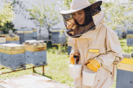 Feliz hembra apicultora sonriente sosteniendo miel orgánica preparada hecha en la granja de abejas