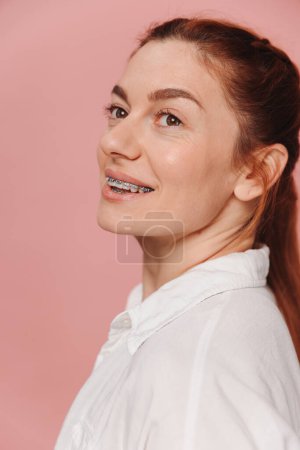Foto de Mujer feliz moderna sonriendo con tirantes sobre fondo rosa, concepto de ortodoncia - Imagen libre de derechos