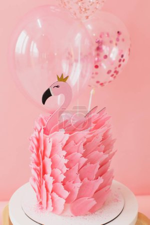 Foto de Bonita tarta rosa con flamenco sobre papel rosa y fondo de globos en estudio - Imagen libre de derechos