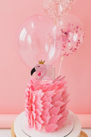 Foto de Bonita tarta rosa con flamenco sobre papel rosa y fondo de globos en estudio - Imagen libre de derechos