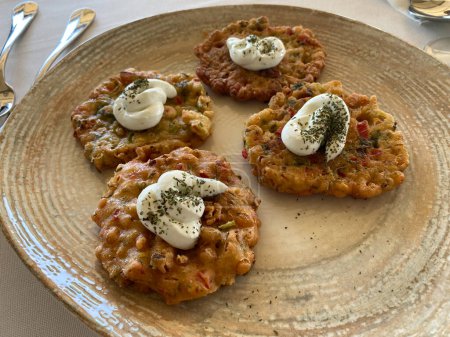 Zucchini fritters, vegetarian zucchini pancakes, served with fresh herbs and sour cream. traditional food.