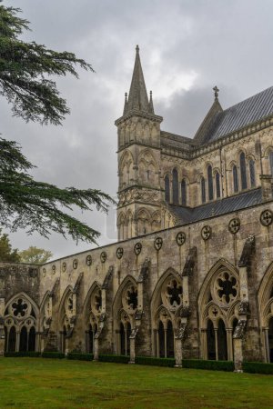 Téléchargez les photos : Salisbury, Royaume-Uni - 8 septembre 2022 : vue sur la flèche et le cloître de la cathédrale de Salisbury par temps pluvieux et couvert - en image libre de droit