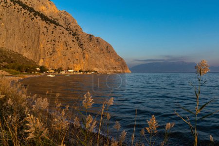 Foto de La pequeña aldea de pescadores de Kryoneri en el Golfo de Corinto con la montaña Vasarova al atardecer - Imagen libre de derechos